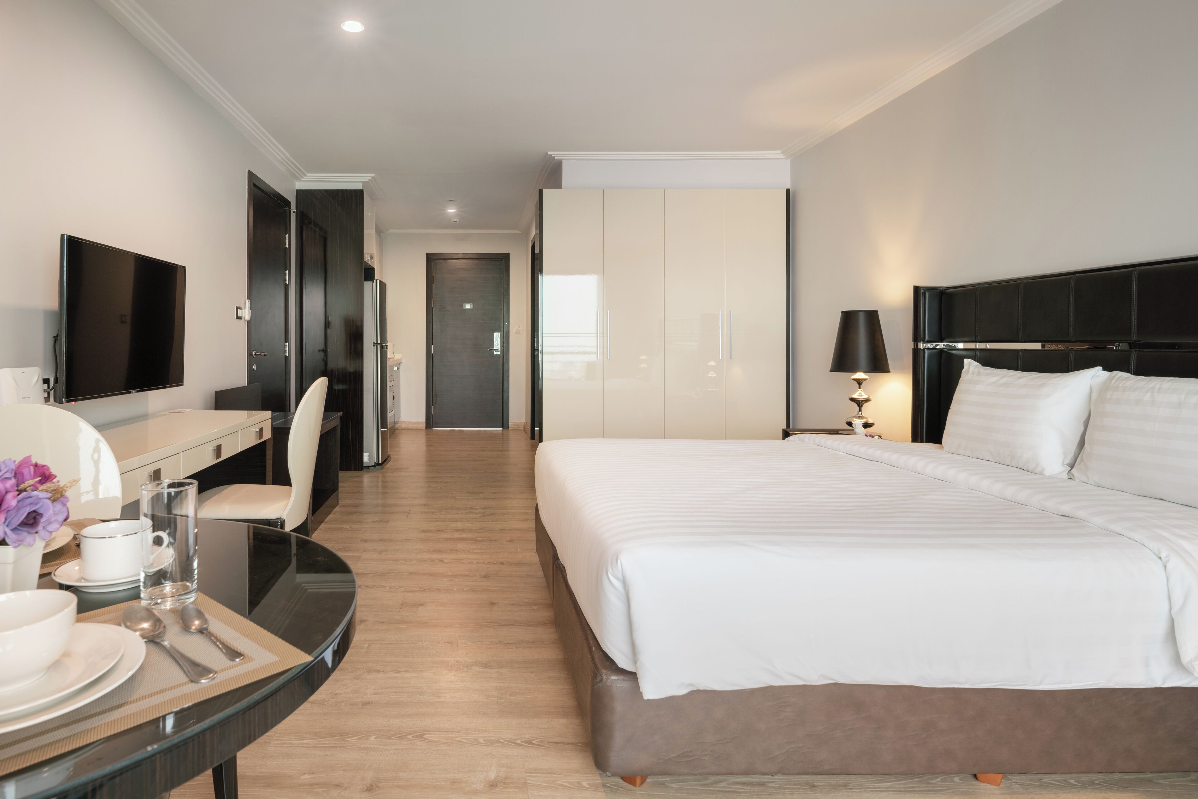 Een moderne hotelkamer met een groot bed, een bureau met stoel, een flatscreen televisie en een zithoek met tafel en stoelen.