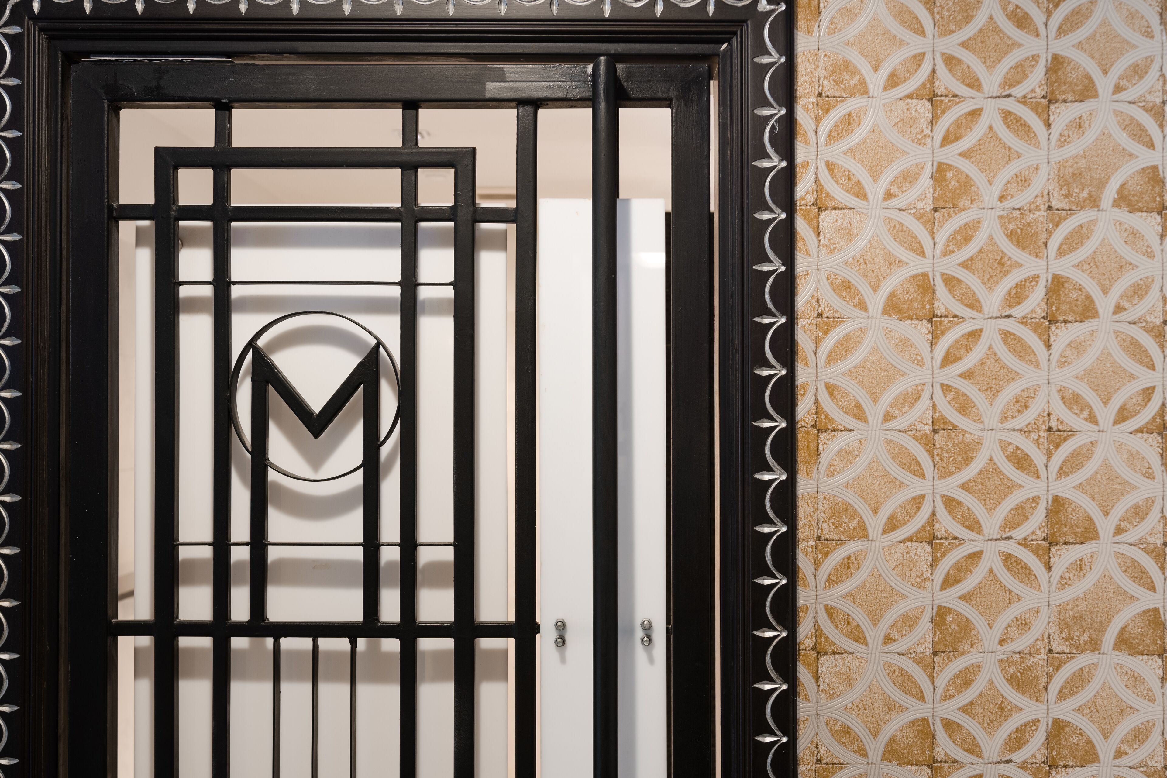 Une porte en métal noir, avec une porte blanche et un logo au centre.