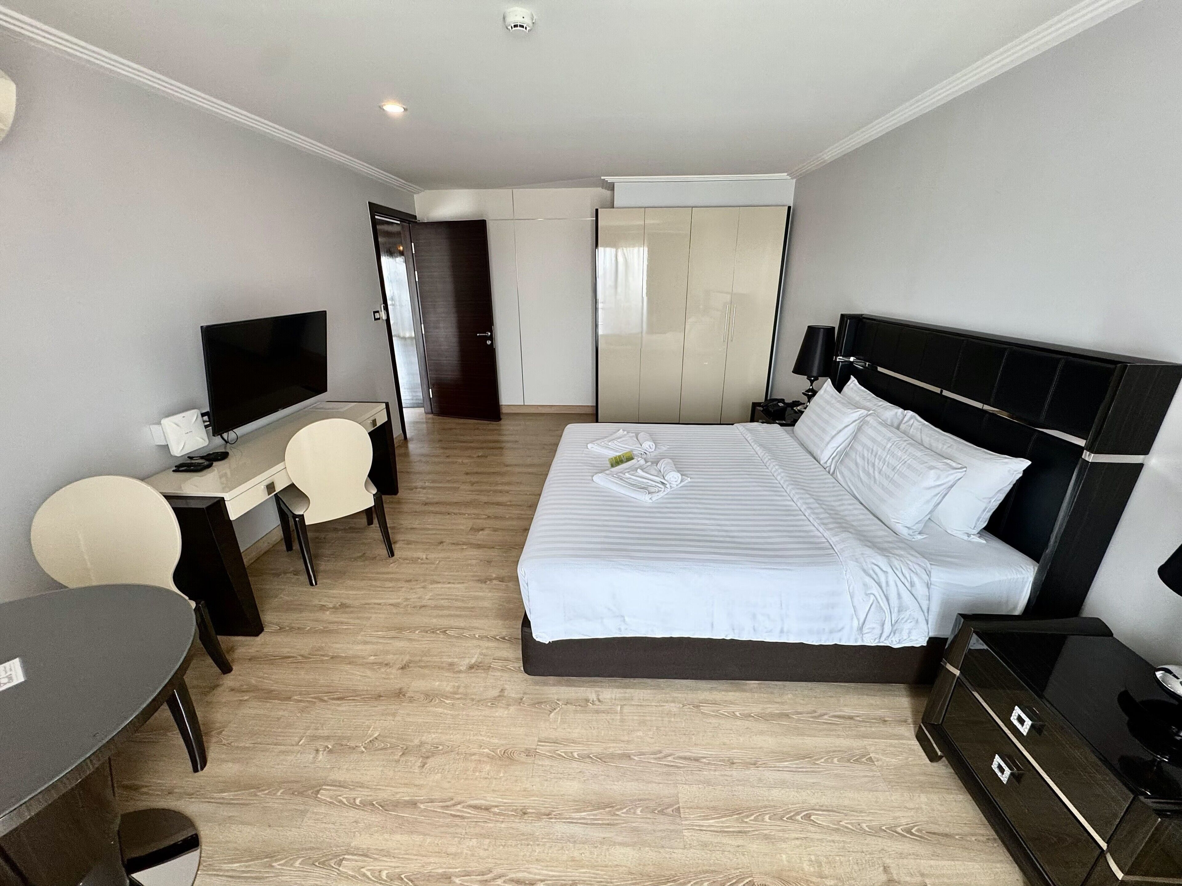 A hotel room with a bed, a desk with a chair, a television, and a wardrobe.