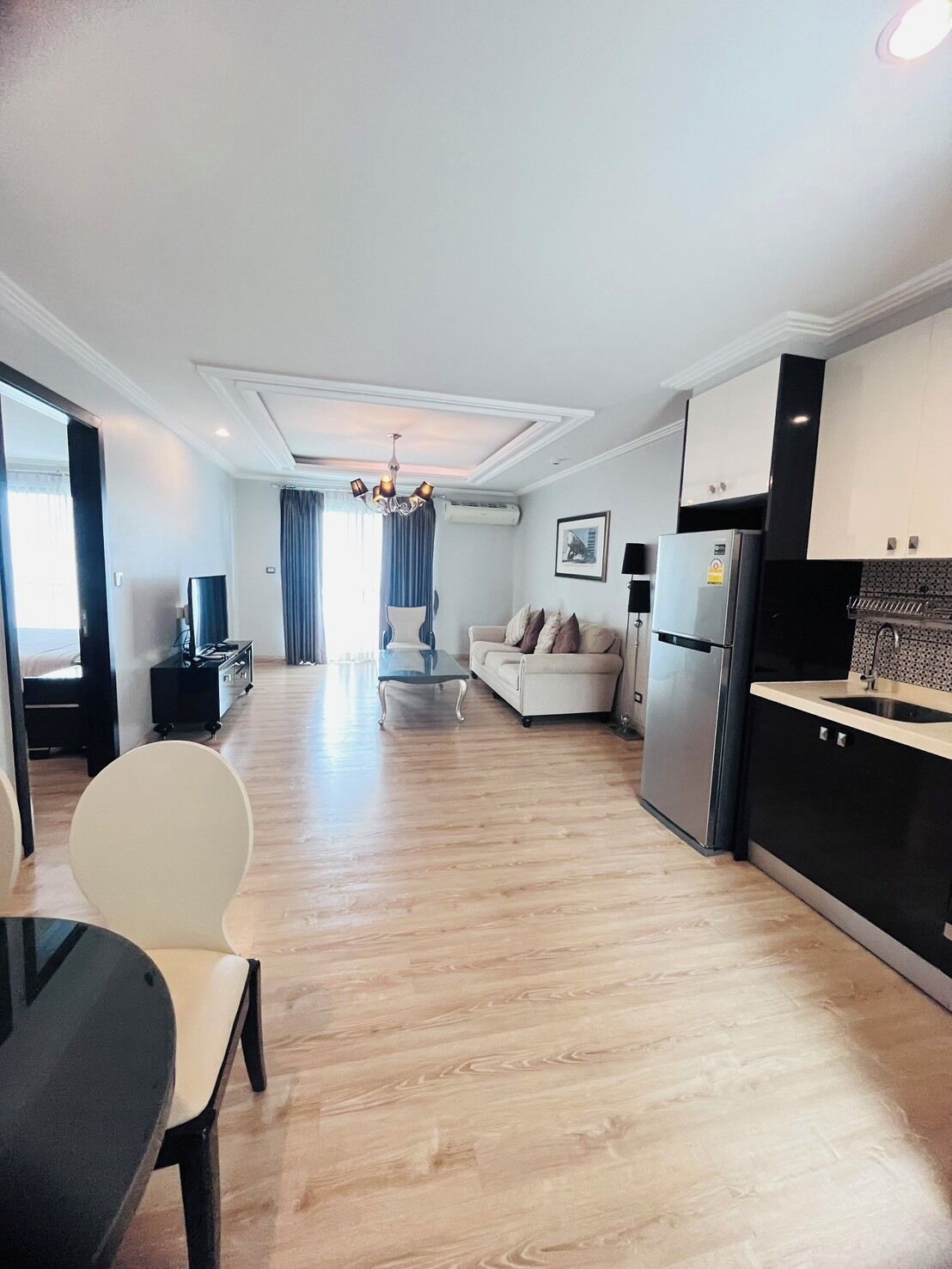 A modern apartment with a dining area, a sofa, a kitchen, and a living room.