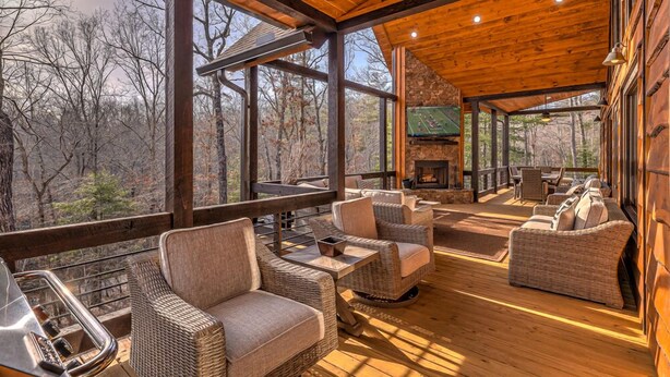 A wooden deck with wicker furniture, a stone fireplace, and a TV screen. - Luxe Mountain Retreat - Pet Friendly | Multiple Outdoor Living Areas | Hot Tub | Game Room (Blue Ridge)