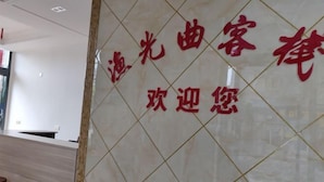 A reception area with a tiled wall and a wooden reception desk. - Taicang Your Crown Trip Inn (Taicang)