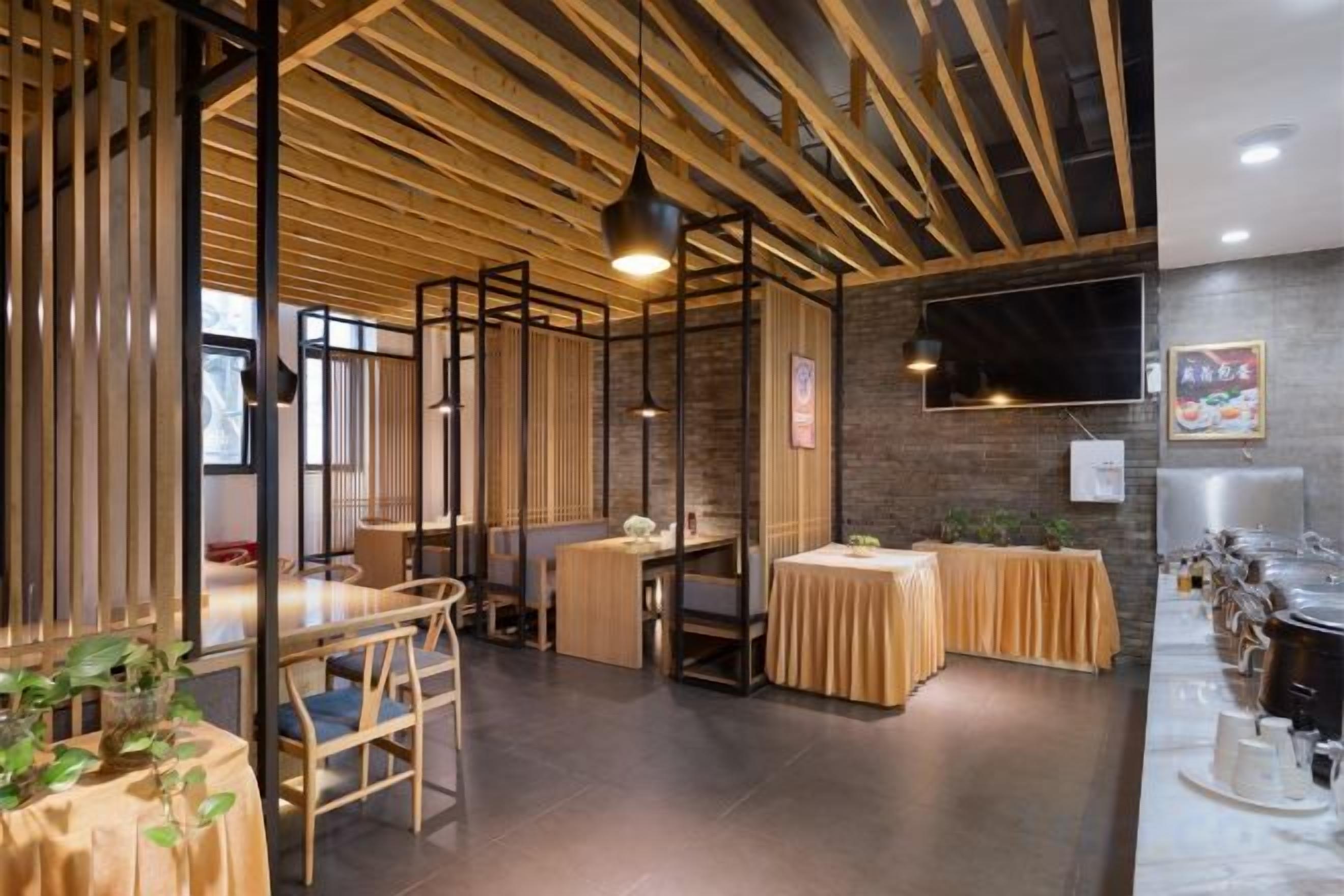 A restaurant with wooden beams, tables, chairs, and a brick wall.