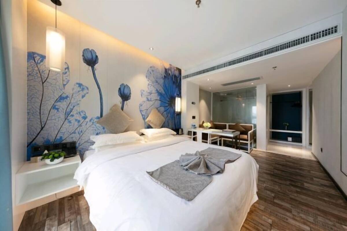 A modern hotel room with a large bed, a desk, and a seating area.