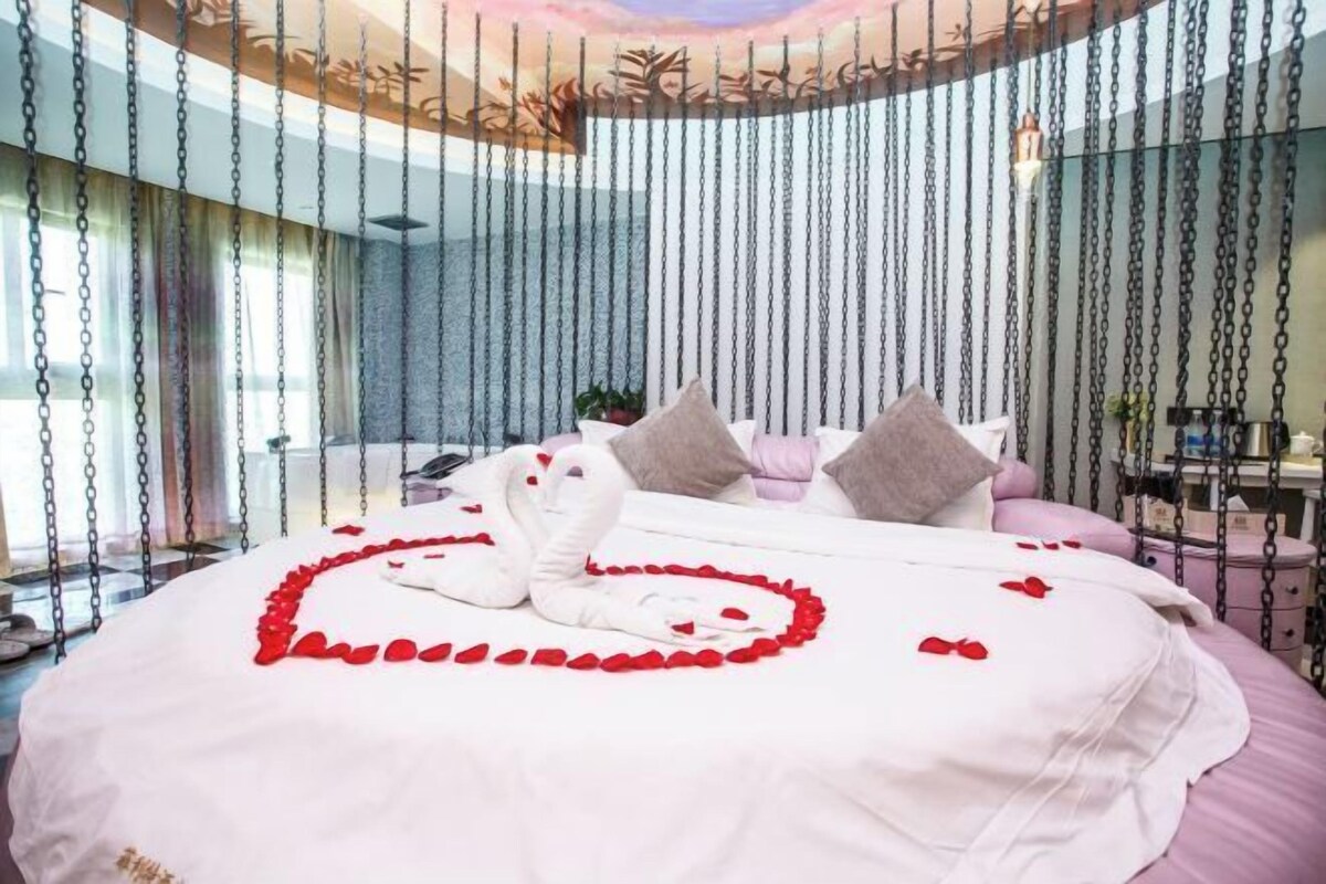 Quarto com cama, almofadas e decoração em formato de coração feita de pétalas de rosa.