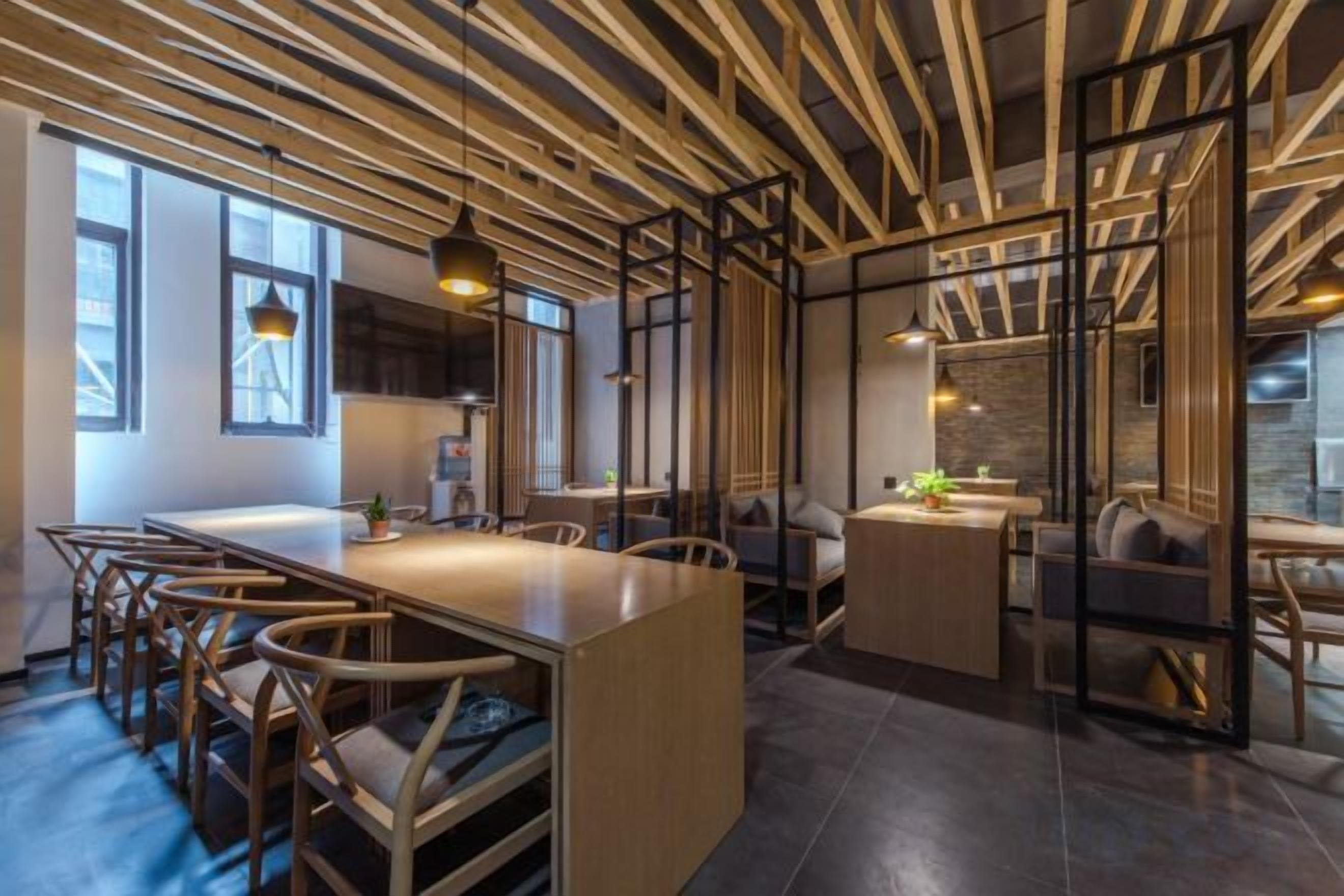 A modern interior with a long dining table, chairs, and a kitchen area.