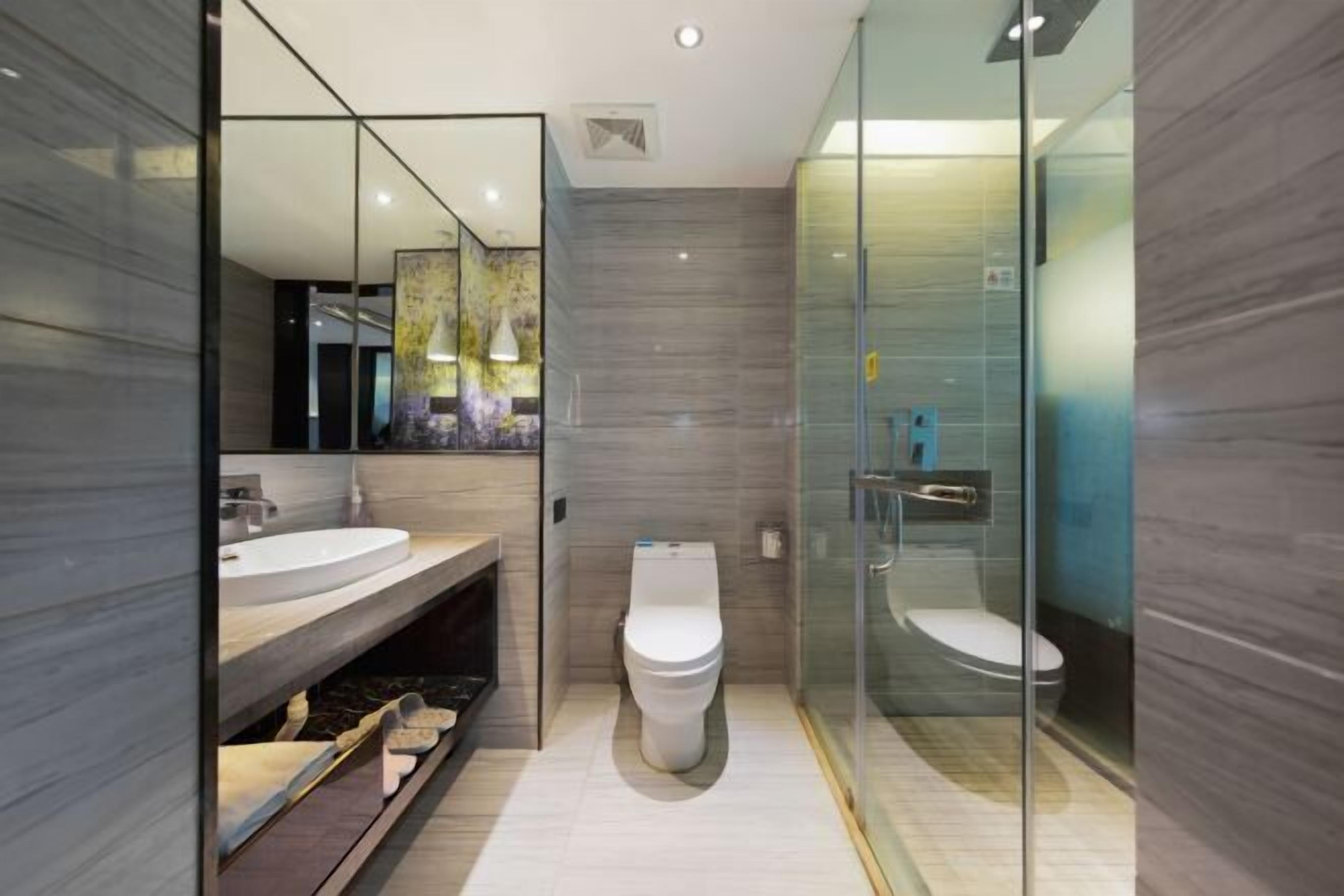 A modern bathroom with a glass-enclosed shower, a white toilet, and a vanity with a large mirror.