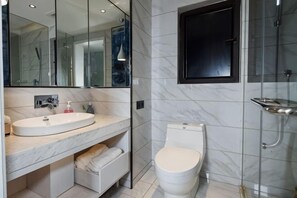 A bathroom with a marble sink, a toilet, a glass shower enclosure, and a mirror. - Feilite Hotel (Kunming)