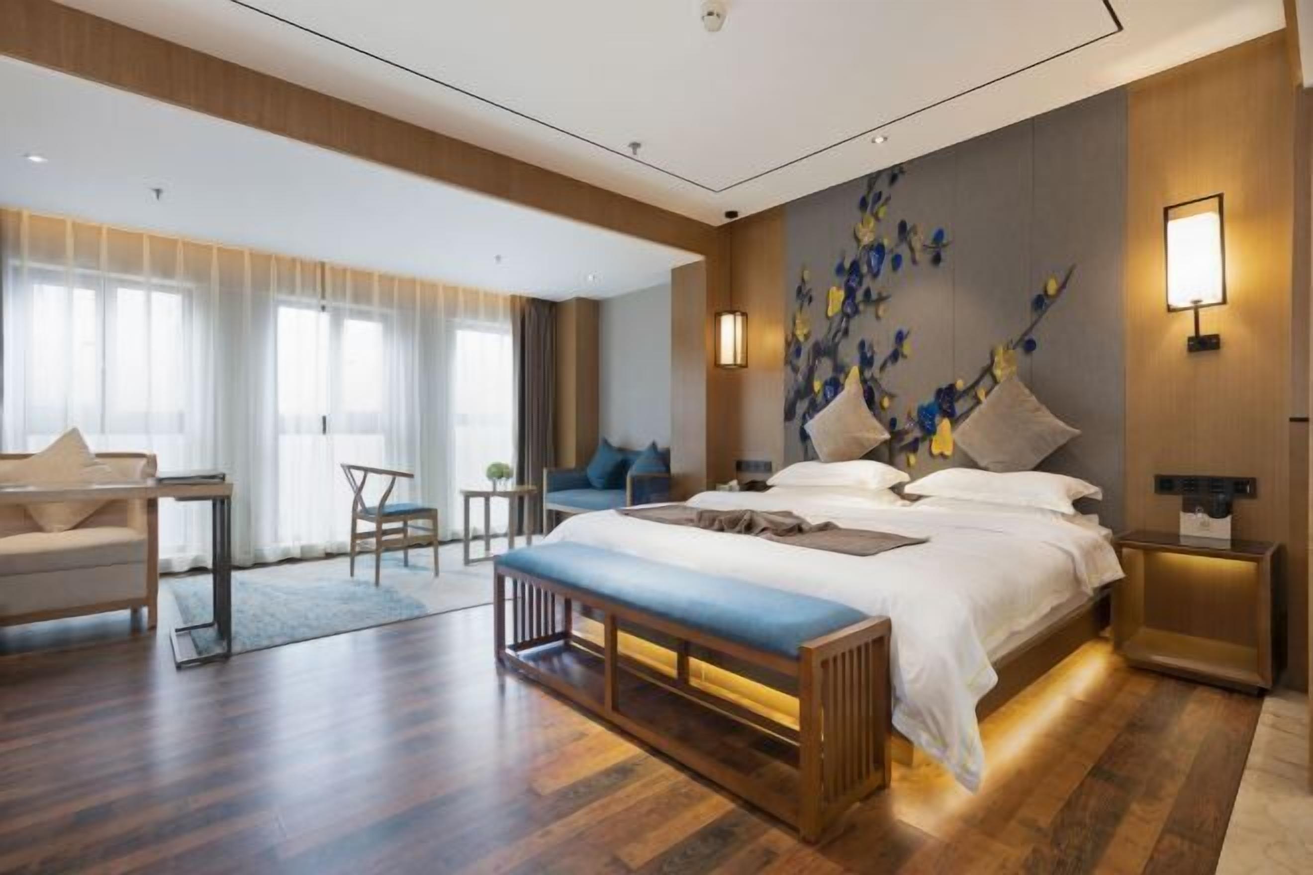 Et moderne hotelværelse med en stor seng, en bænk, et skrivebord og en stol.