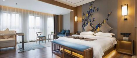 Une chambre d’hôtel moderne avec un grand lit, une banquette, un bureau et une chaise.