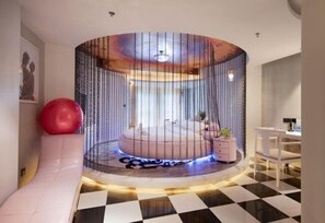 A circular room with a bed, a red exercise ball, and a white chair. - Feilite Hotel (Kunming)