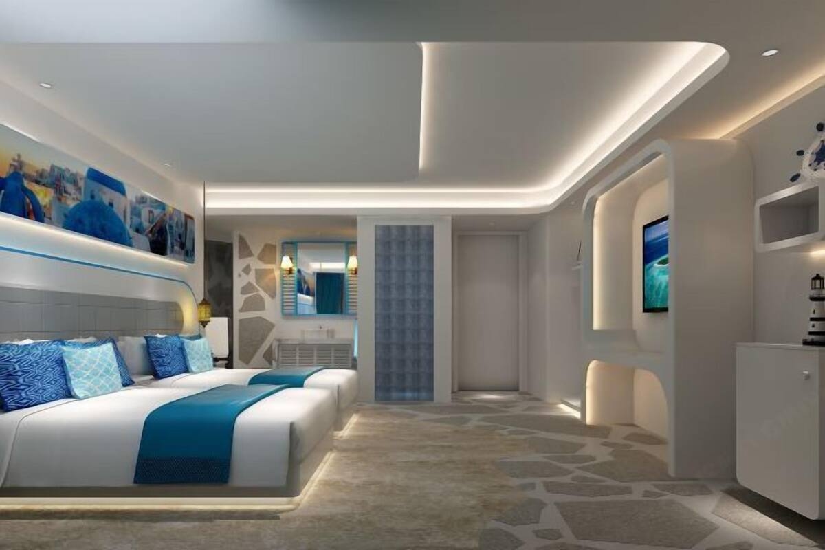 A modern hotel room with a large bed, a TV, and a minibar.