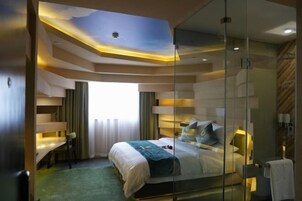 Una habitación de hotel moderna con una cama grande, un escritorio y un separador de vidrio.