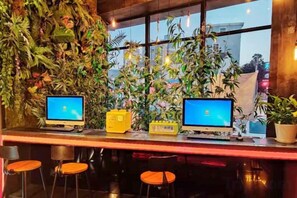 Zona de bar con dos computadoras, una planta en maceta y vistas al exterior.