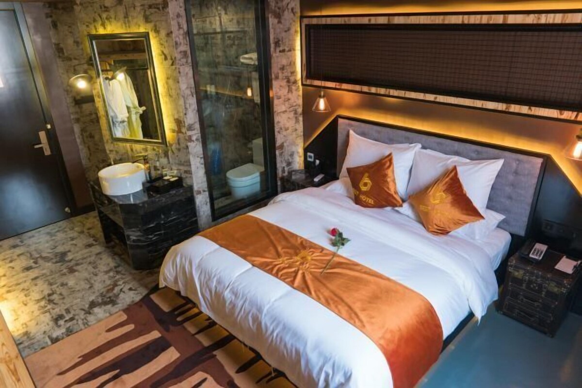 Una habitación de hotel con una cama grande, un baño con lavamanos de mármol y cabina de ducha de vidrio.