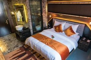 Una habitación de hotel con una cama grande, un baño con lavamanos de mármol y cabina de ducha de vidrio.