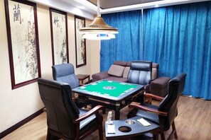 Una habitación con una mesa de blackjack de fieltro verde, sillas de cuero, una cortina azul y arte tradicional en la pared.