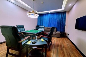 Una habitación con mesa de billar, cuatro sillas, un sofá y televisor.