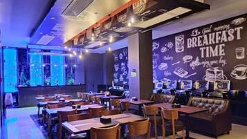 Un restaurante con mesas y sillas, una barra y una pared decorada con imágenes relacionadas con el desayuno.