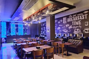 A restaurant with tables and chairs, a counter, and a wall with breakfast-related graphics. - Bosite Boutique Theme Hotel (Taizhou)