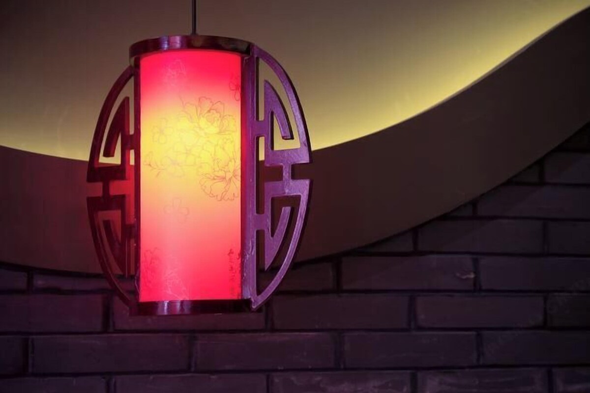 Un farol colgante con luz roja, sujeto a una pared de ladrillo.