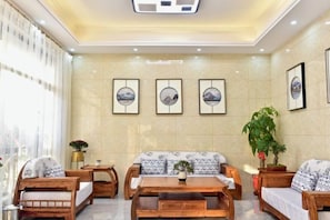 A hotel lobby with a sofa set, wooden coffee table, and framed artwork on the wall.