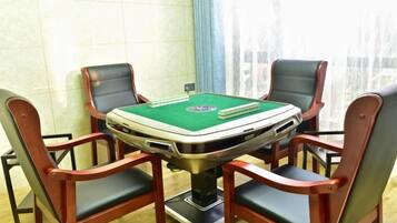A poker table with four chairs, a green felt surface, and playing cards.