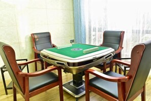 A poker table with four chairs, a green felt surface, and playing cards.