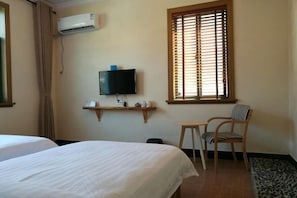 A hotel room with two beds, a TV mounted on the wall, a window with blinds, a small table, and a chair. - Qingmei Zhuma Inn (Deqing)