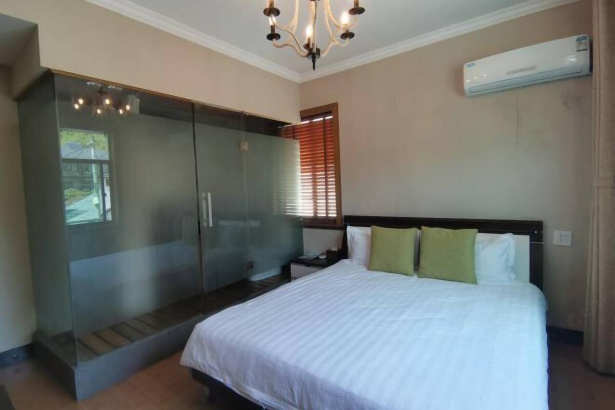 A bedroom with a bed, a nightstand, a dresser, and a glass-enclosed closet.
