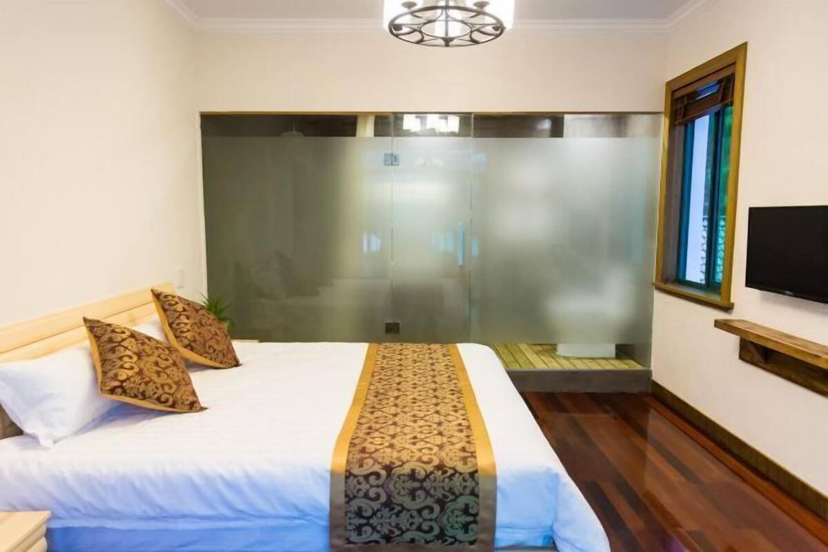 A hotel room with a bed, a television, a window, and a sliding door.
