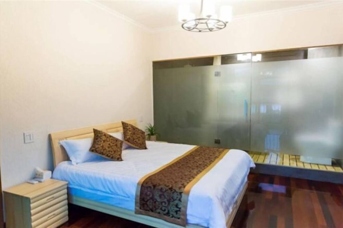 A hotel room with a bed, bedside table, and a large mirror.