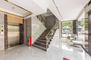 A modern lobby with a marble floor, a staircase, a glass elevator, and a seating area with a plant. - Boli Hotel Guangzhou (Guangzhou)