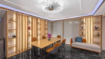 Uma sala de jantar moderna com mesa de madeira, cadeiras e prateleiras embutidas com objetos decorativos.