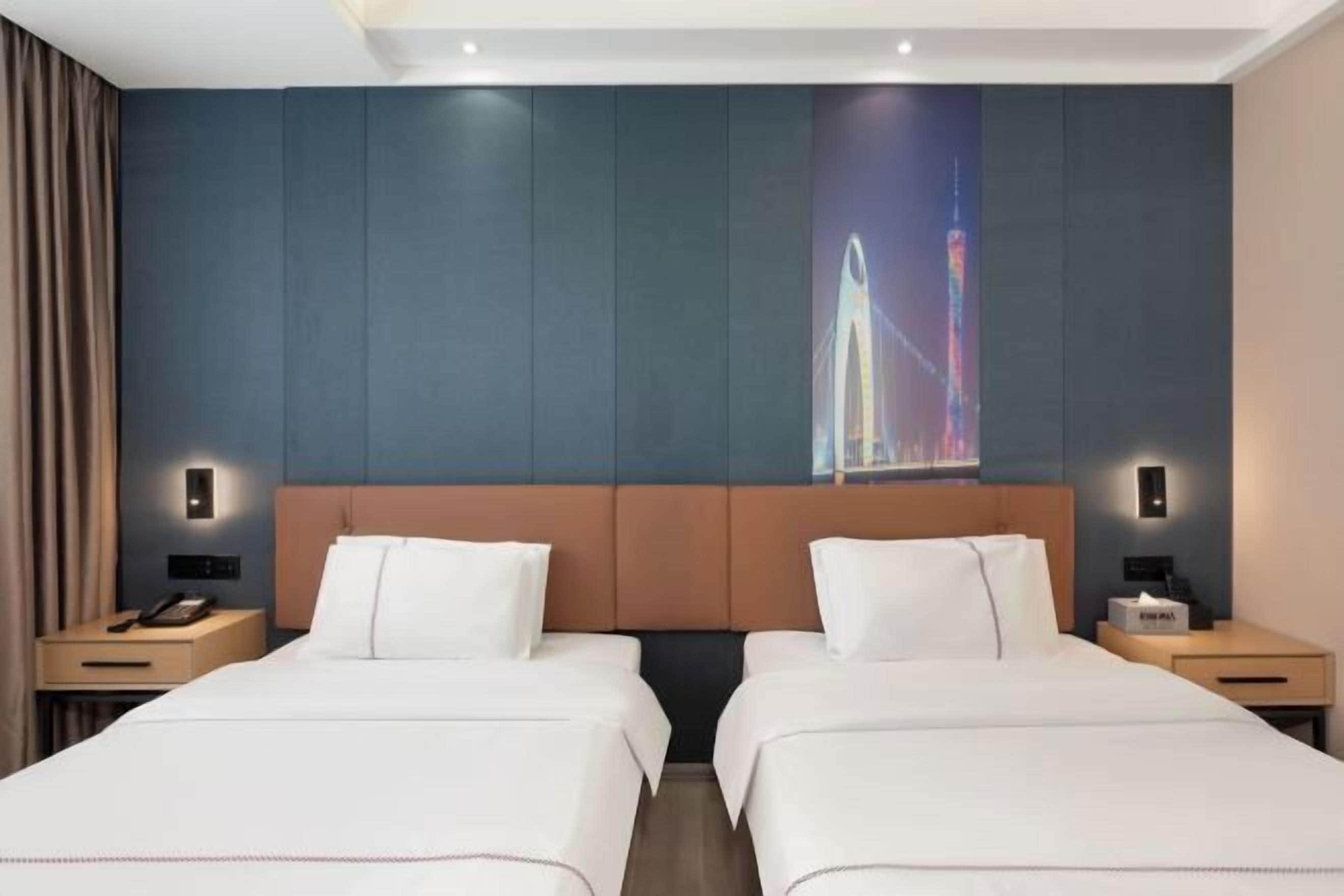 Ein Hotelzimmer mit zwei Betten, einem großen Wandbild und einem Nachttisch mit Telefon und Taschentuchbox.