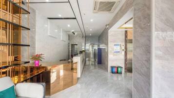 A hotel lobby with a reception desk, seating area, and a staircase leading to the upper floors.