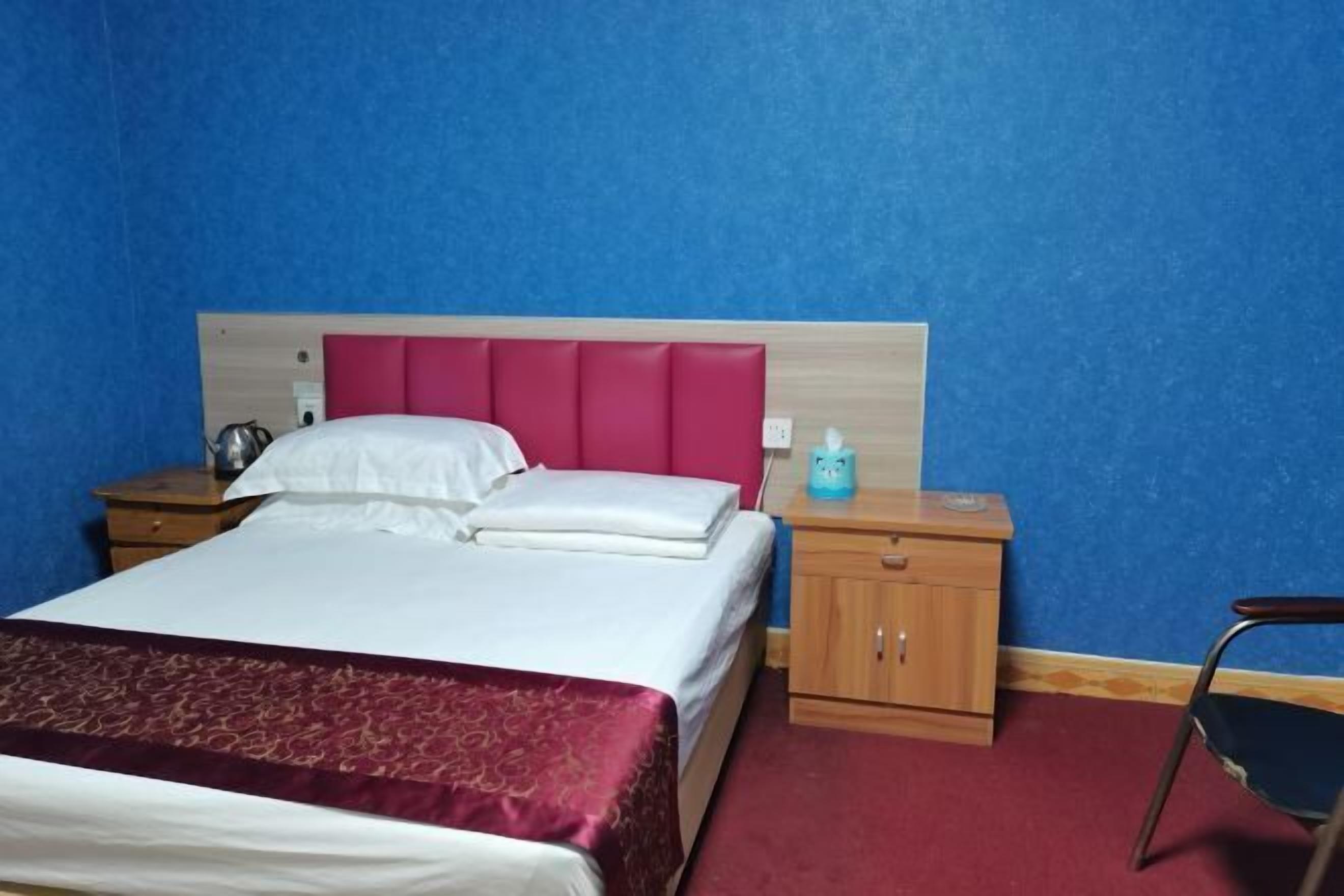 A hotel room with a bed, a nightstand, a chair, and a wooden cabinet.