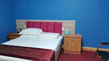 A hotel room with a bed, a nightstand, a chair, and a wooden cabinet.