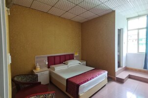 Una habitación de hotel con cama, mesita de noche y un escritorio pequeño con silla.