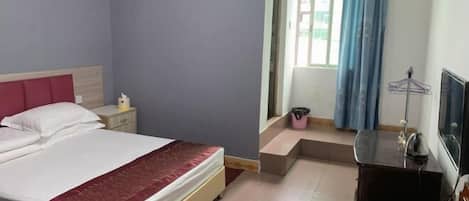 A hotel room with a bed, a nightstand, a desk, a TV, and a window with curtains.