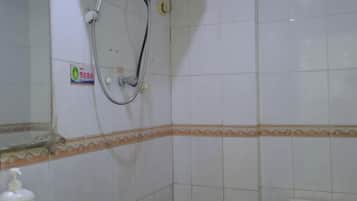 A bathroom with white tiles, a shower, a toilet, and a soap dispenser.