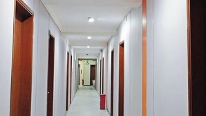 A long, narrow hotel corridor with doors on both sides, a trash bin in the center, and a ceiling light. - Dexin Hotel Taishan (Taishan)