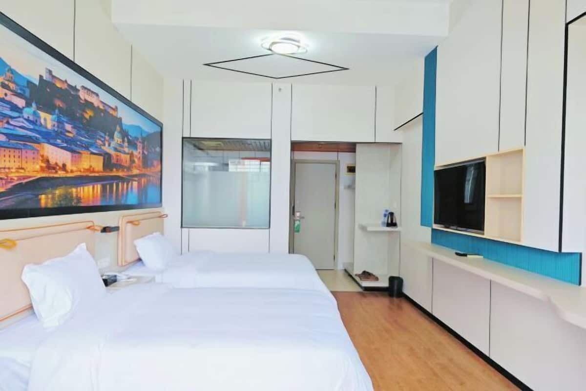 A hotel room with two beds, a large painting, a TV, and a wardrobe.
