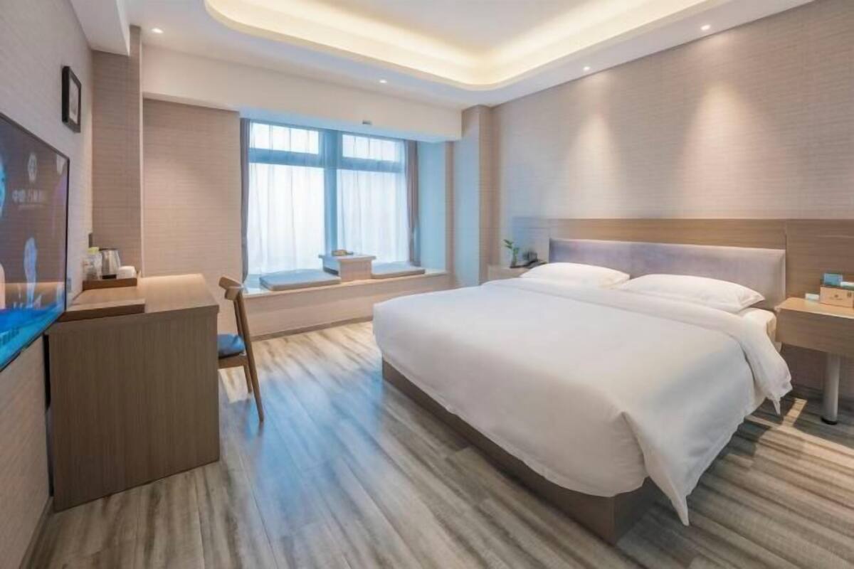 Una habitación de hotel con una cama grande, un escritorio, una ventana con cortinas y un diseño moderno.
