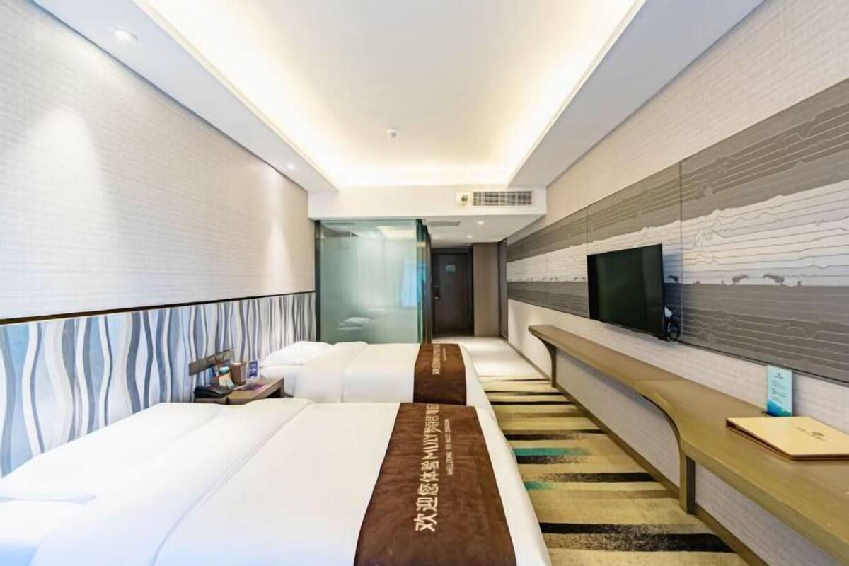 Habitación de hotel con dos camas, televisión, escritorio y pared con diseño.