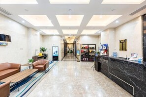 A hotel lobby with a reception desk, seating area, and a hallway leading to the rooms. - Midland Marriott Hotel (West Coast New Area City Balcony Branch) (Qingdao)