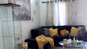 A living room with a black sofa, a glass cabinet, and a coffee table.
