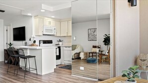 A modern kitchen with white cabinets, a microwave, and a stove. There is a dining area with a wooden table and chairs. -  NO PARKING & RESORT FEE IN WEST MAUI WITH AMAZING OCEAN VIEW CONDO (Lahaina)