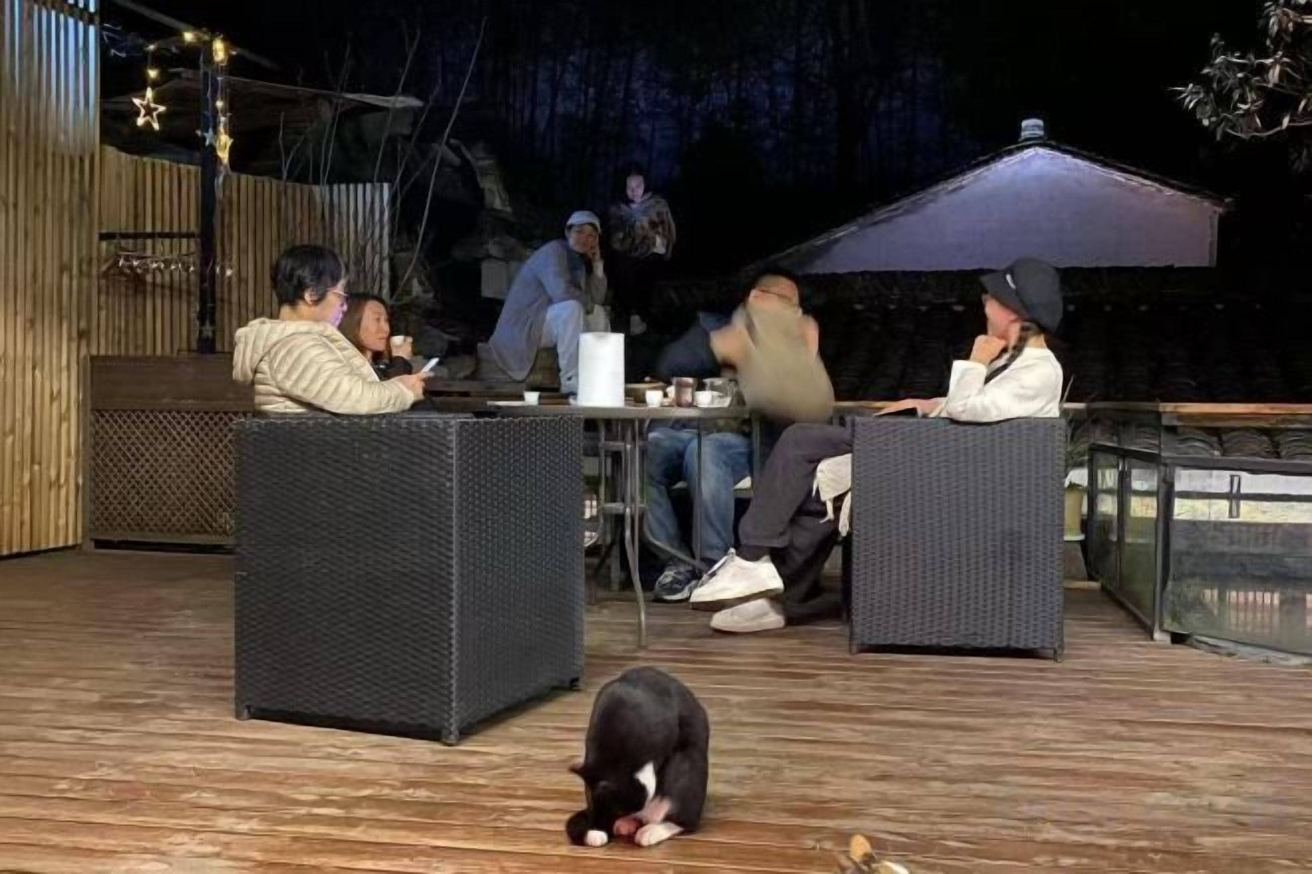 An outdoor seating area with wicker furniture, a wooden deck, and a glass railing.