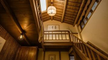 Interior de madeira com escada, luminária pendente e quadro na parede.